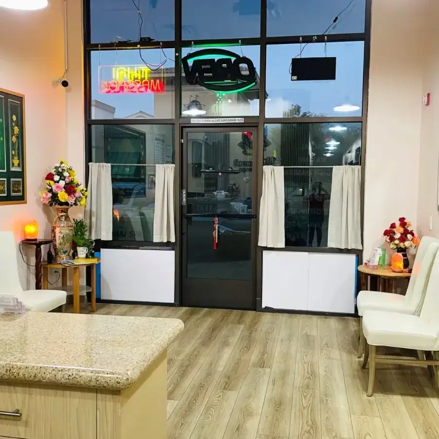 The bright and clean lobby of Blue Diamond Thai Spa & Massage featuring white chairs and floral decor